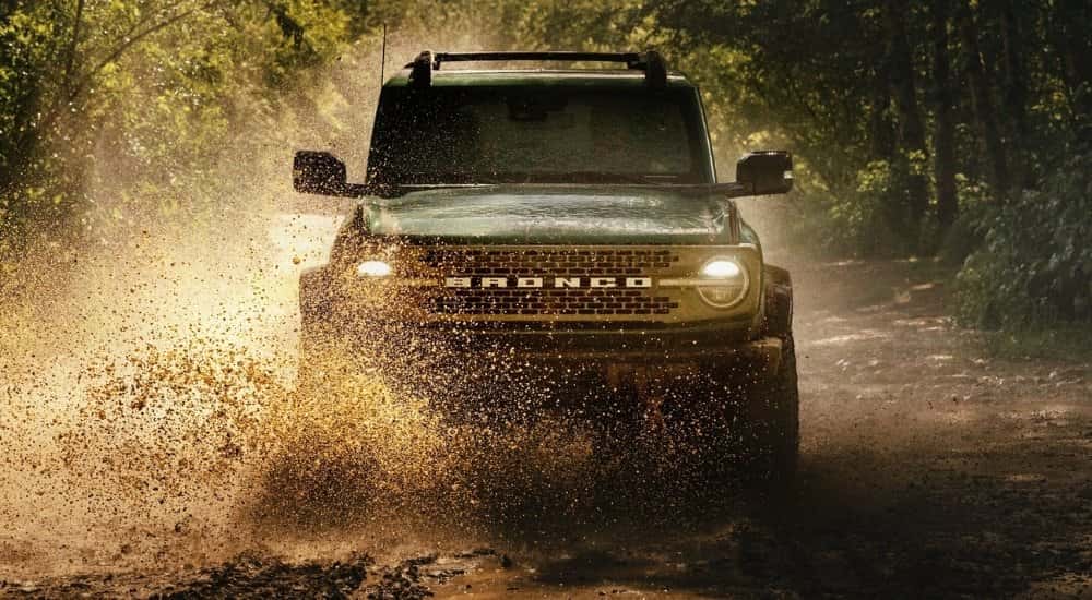 A green 2026 Ford Bronco off-roading in mud