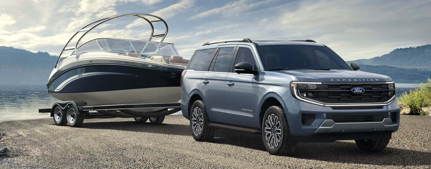 Blue 2026 Ford Expedition Platinum towing a boat out of a lake.