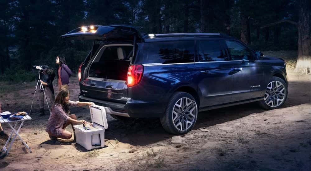 A dark blue 2026 Ford Expedition® MAX Platinum® SUV with available 360-degree Zone Lighting with people nearby.