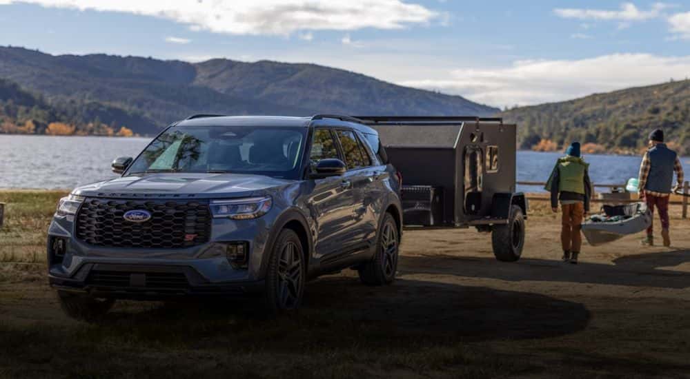 A blue 2026 Ford Explorer parked in front of a lake with a trailer attached.