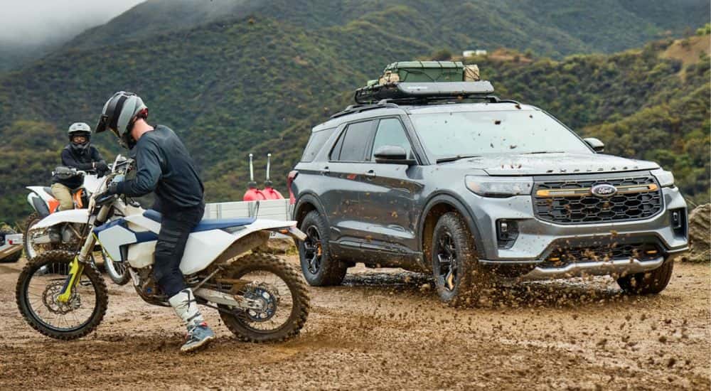 A gray 2026 Ford Explorer parked by people dirtbiking.
