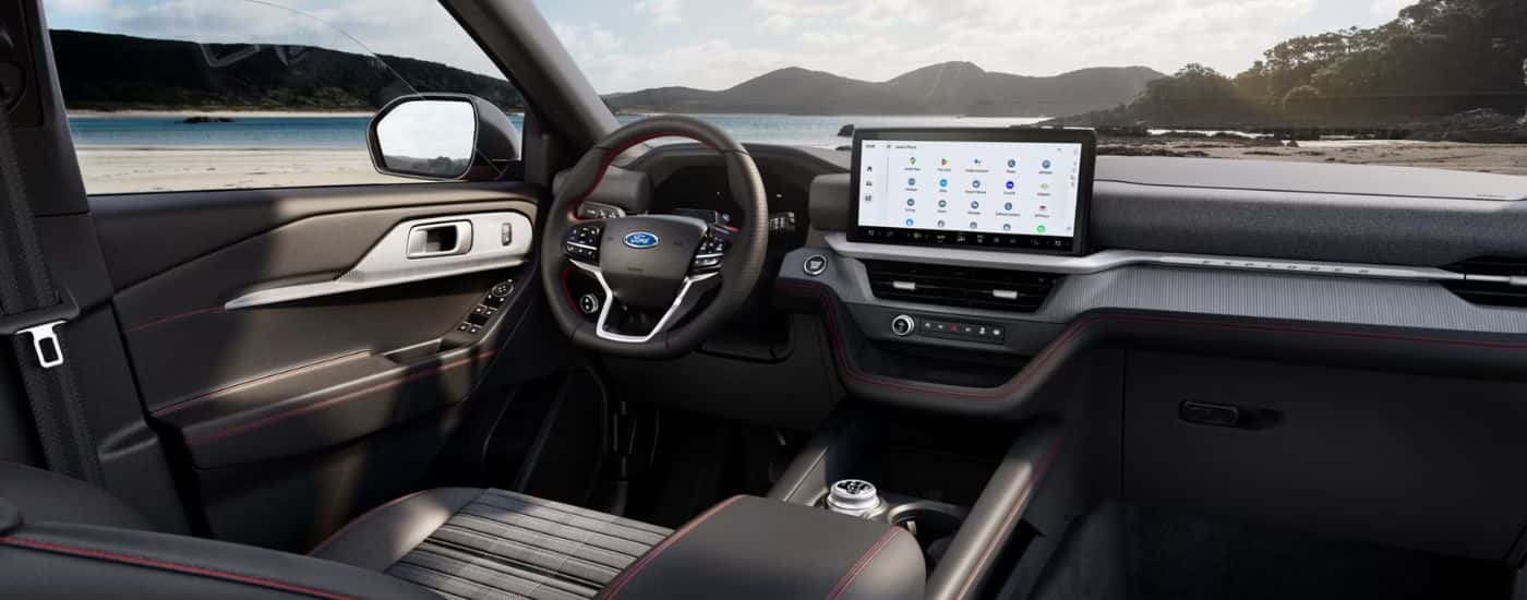 Interior view of a 2026 Ford Explorer infotainment display and steering wheel, parked on a beach.