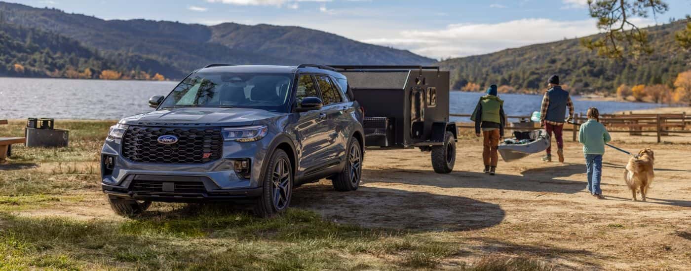 Blue 2026 Ford Explorer with a trailer and family near a lake.