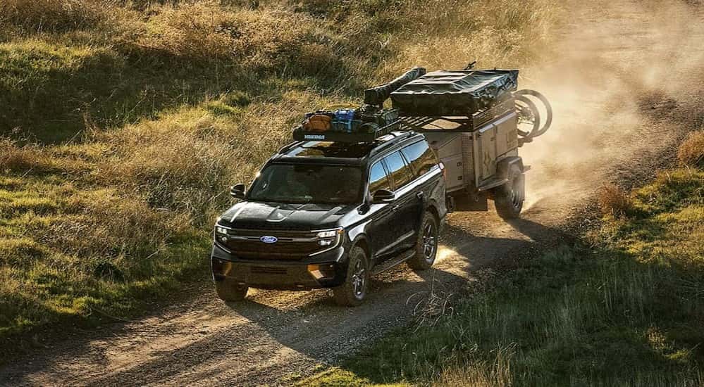 A black 2027 Ford Expedition towing a trailer offroad.