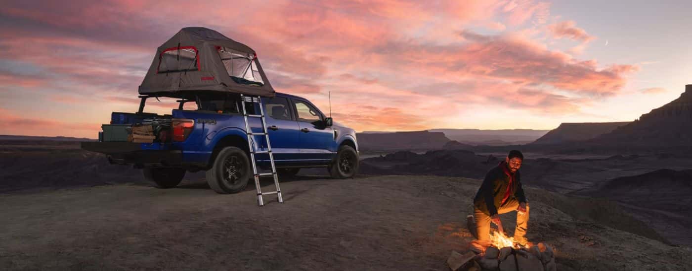 A person camping out of their blue 2026 Ford F-150 STX.