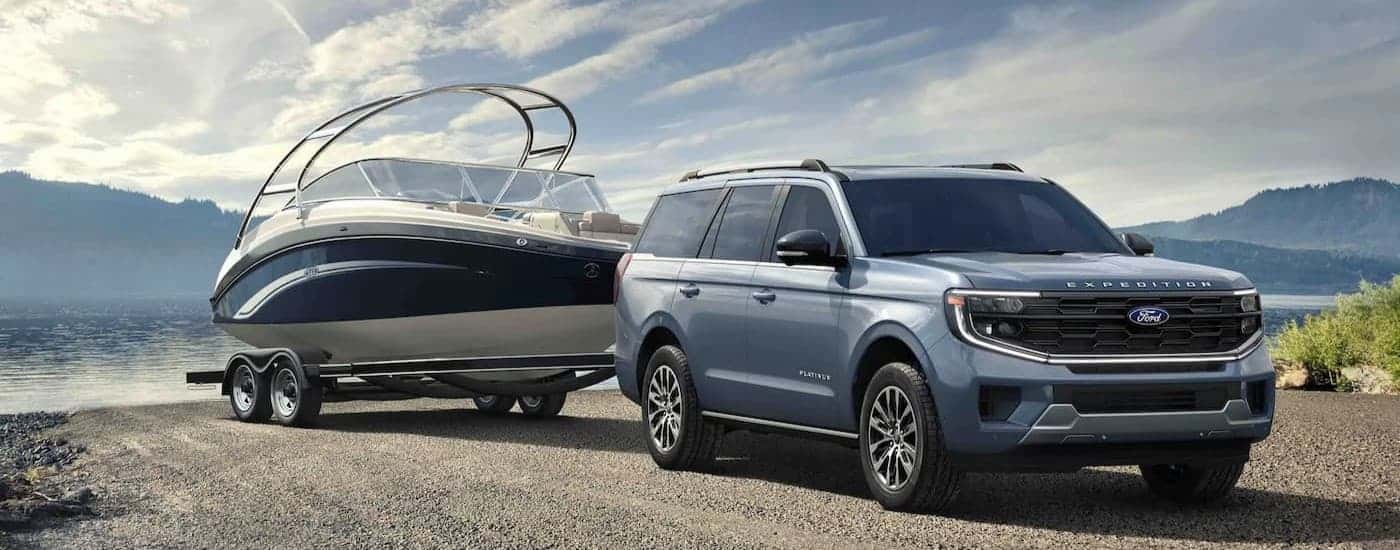A blue 2025 Ford Expedition towing a boat.