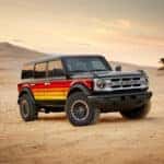 a black ford bronco with red to yellow gradient stripes free wheeling on desert road