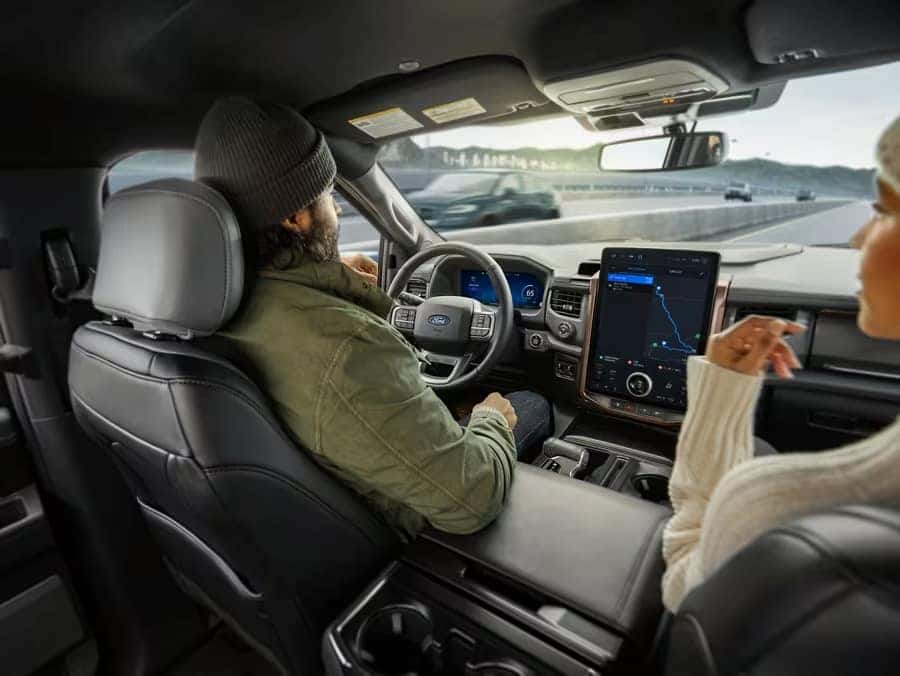 a couple riding on a highway road inside of their Ford electric vehicle