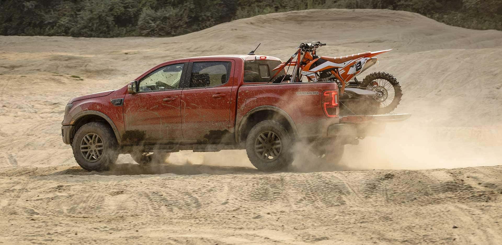 A side shot of a Red Ford Ranger Tremor driving through the dessert.
