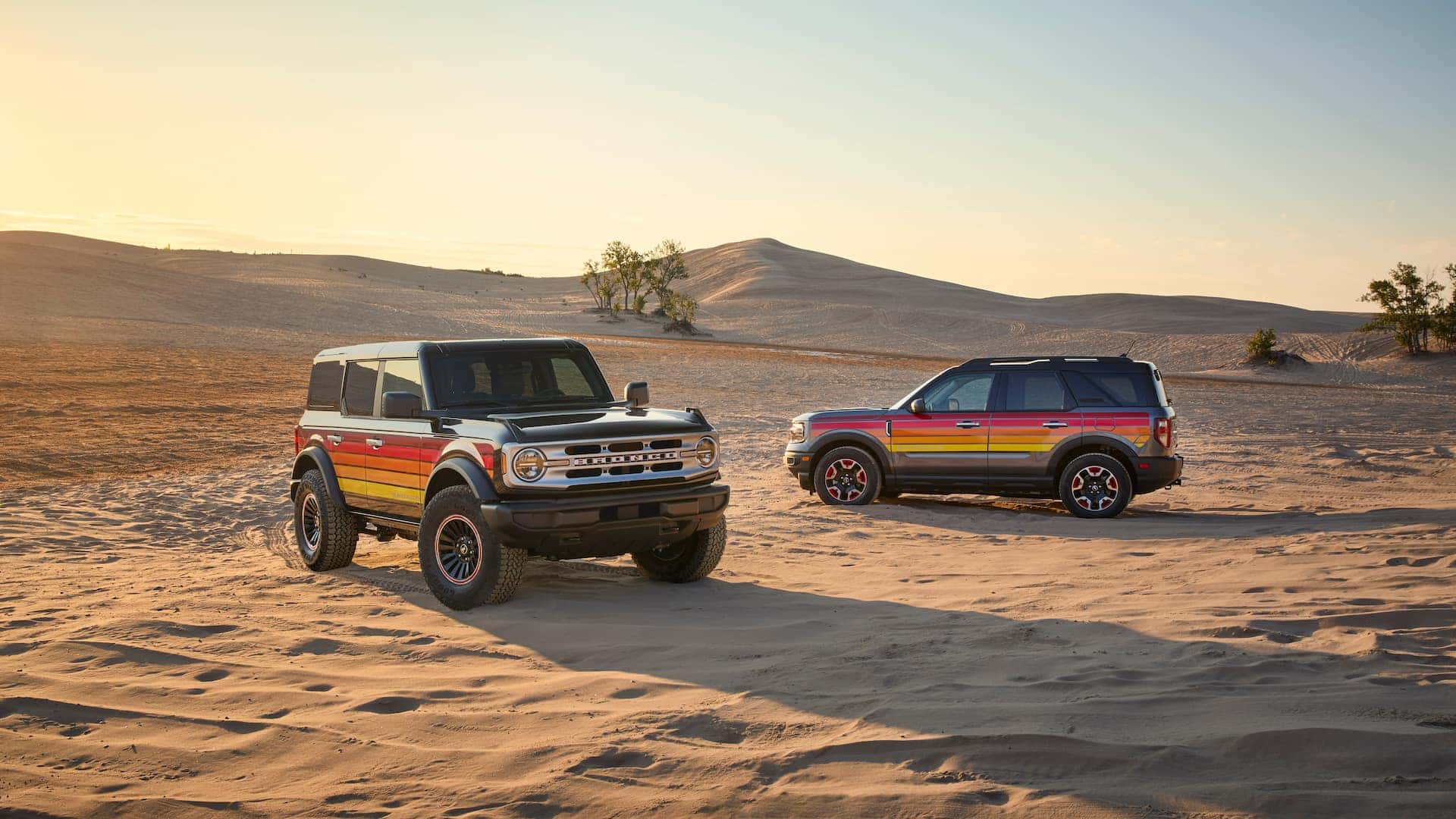 two Ford Broncos side wheeling on a desert road