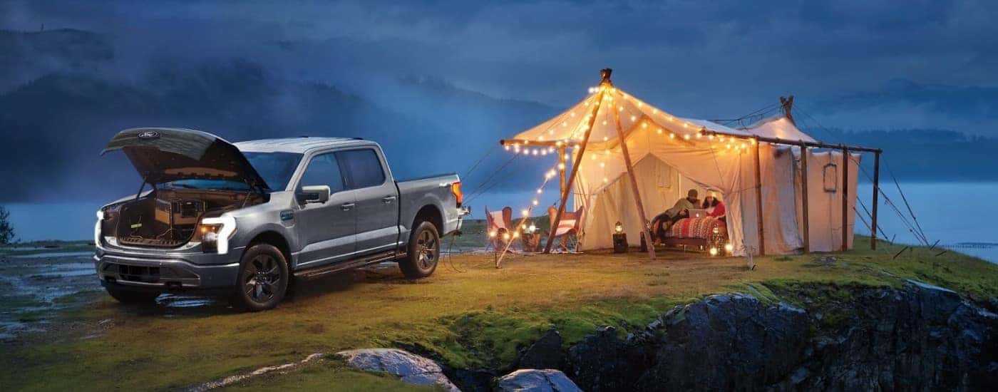 A silver 2024 Ford F-150 Lightning is shown near a tent.
