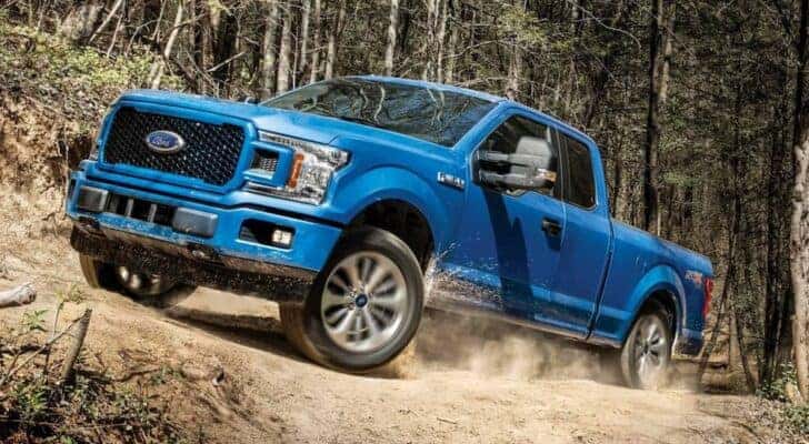 A blue 2019 Ford F-150 driving off-road after viewing a used car dealer near Asheville.