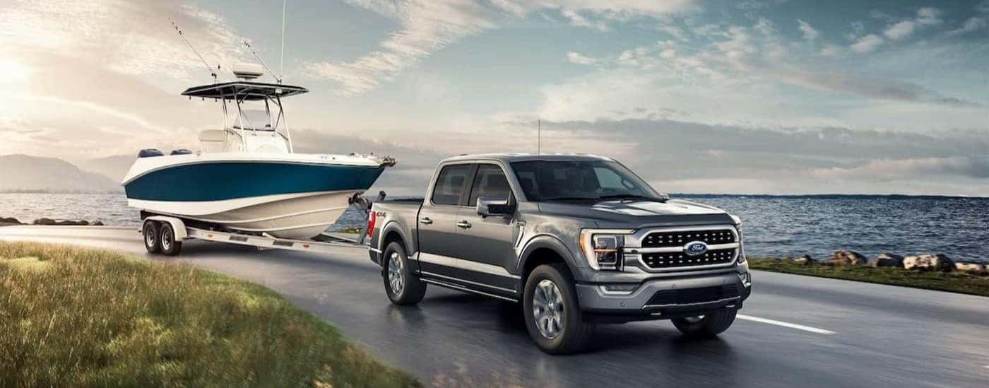 A gray 2023 Ford F-150 Lariat towing a boat.