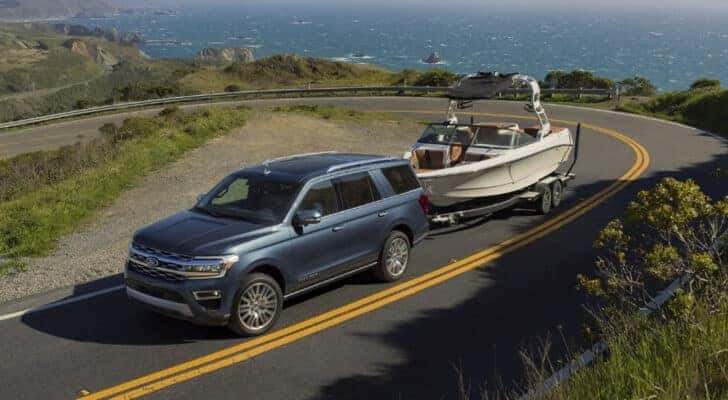 A grey 2023 Ford Expedition Platinum towing a boat to a used car dealer.
