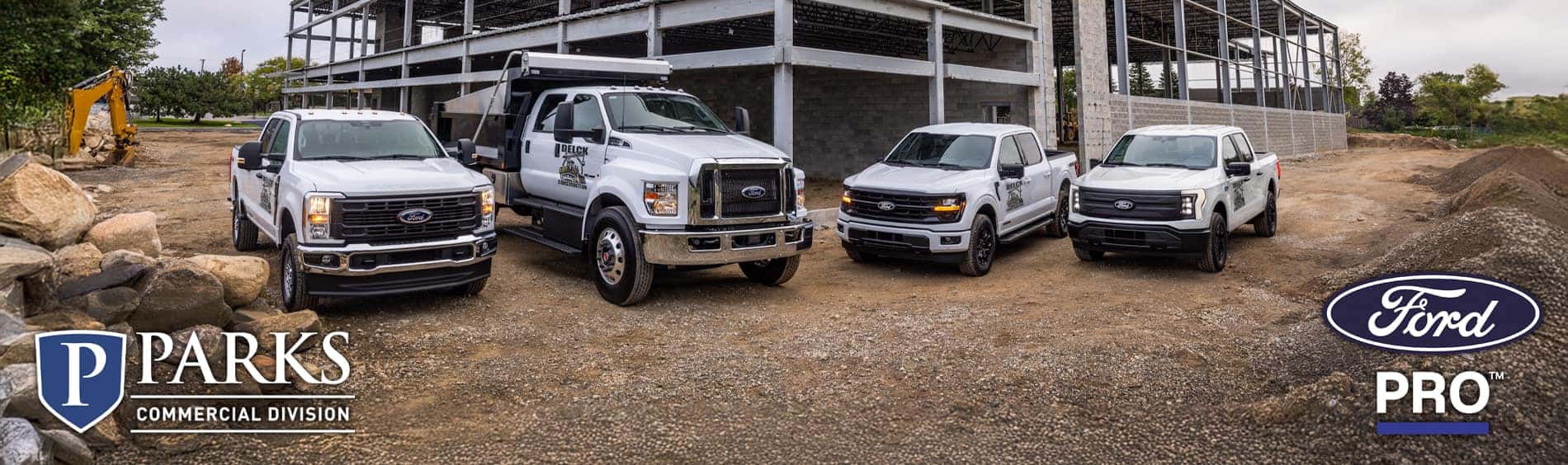 Four white Ford commercial work trucks on a construction site.