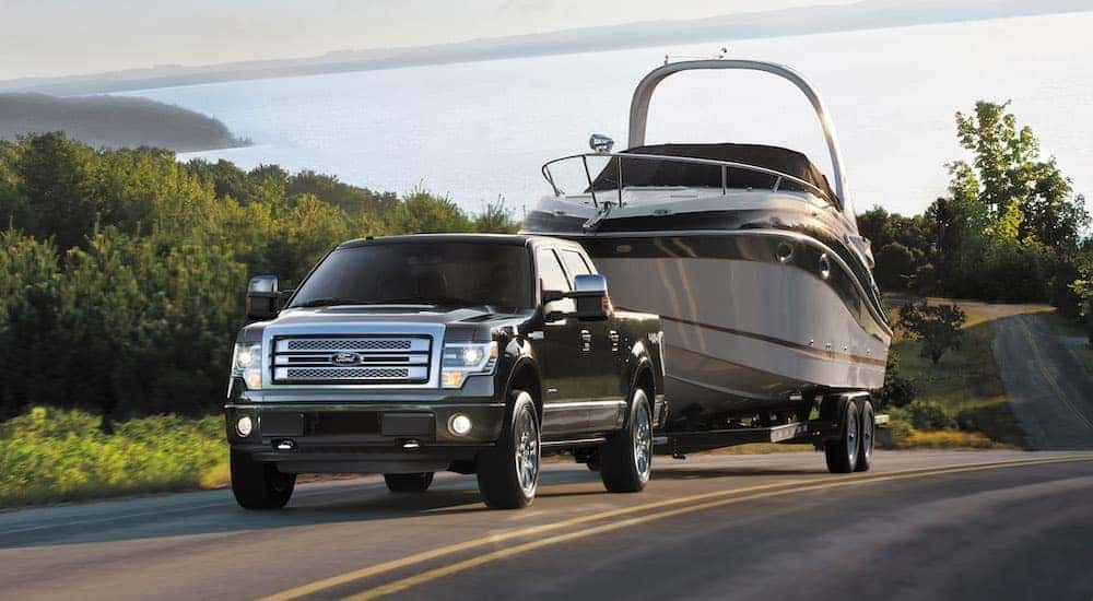A black 2014 Ford F-150 towing a boat after viewing a used Ford F-150 for sale.