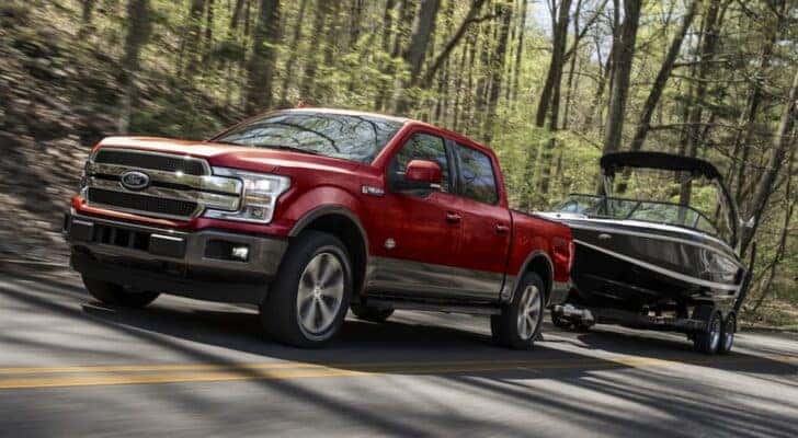 A red 2020 Ford F-150 is shown towing a boat.
