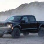 A black 2021 Ford F-150 Raptor is shown parked off-road.