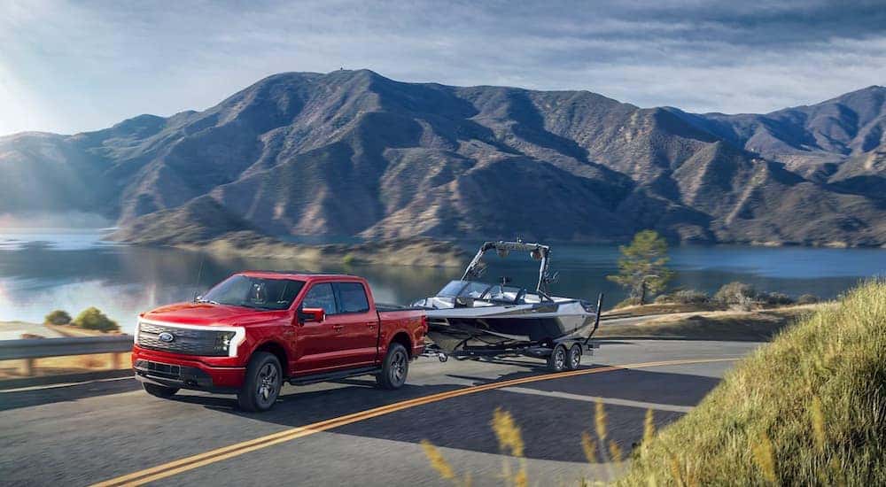 A red 2022 Ford F-150 Lightning towing a boat.