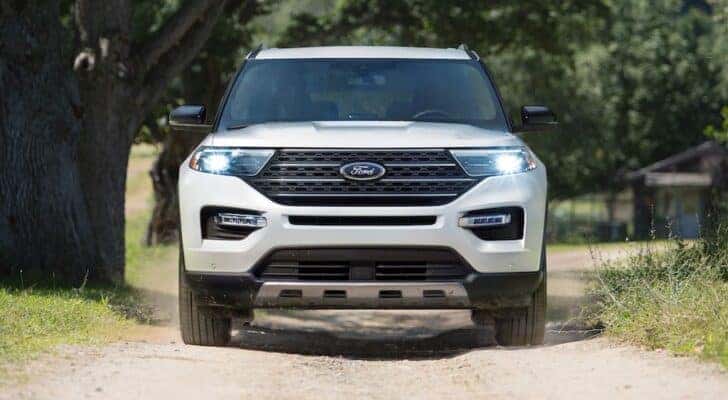 Front angle view of a white 2025 Ford Explorer for sale driving down a road.
