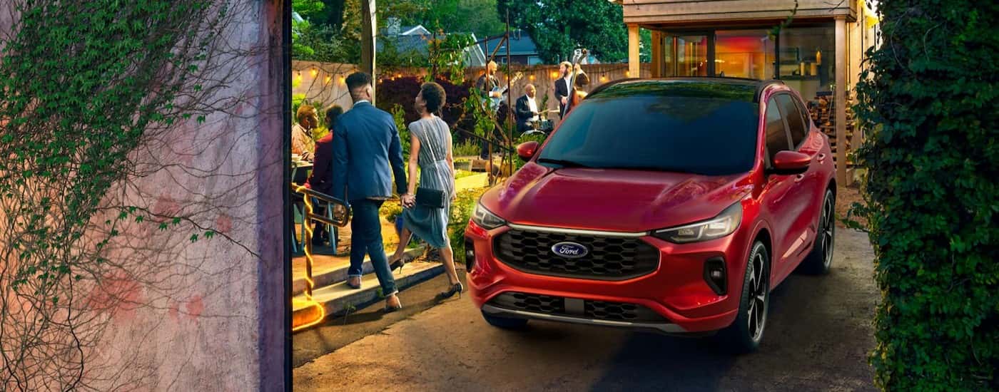 A red 2024 Ford Escape is shown parked near a backyard party.
