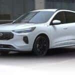 A white 2025 Ford Escape ST-Line driving in a city.