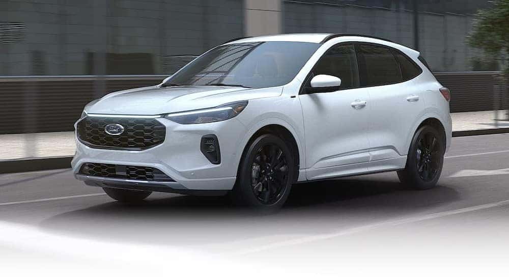 A white 2025 Ford Escape ST-Line driving in a city.