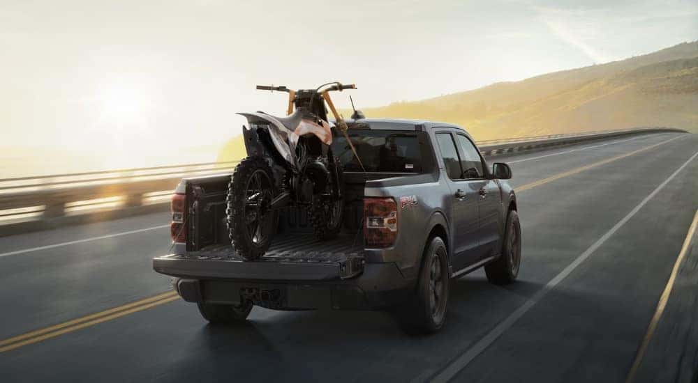 A dark grey 2025 Ford Maverick FX4 is driving on a highway.