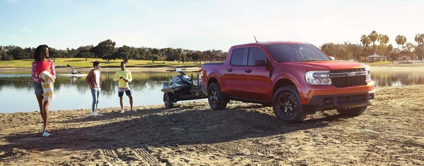 A red 2023 Ford Maverick XLT near a lake.
