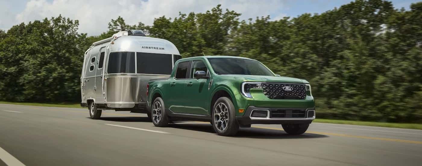 A green 2025 Ford Maverick for sale near me towing a trailer.