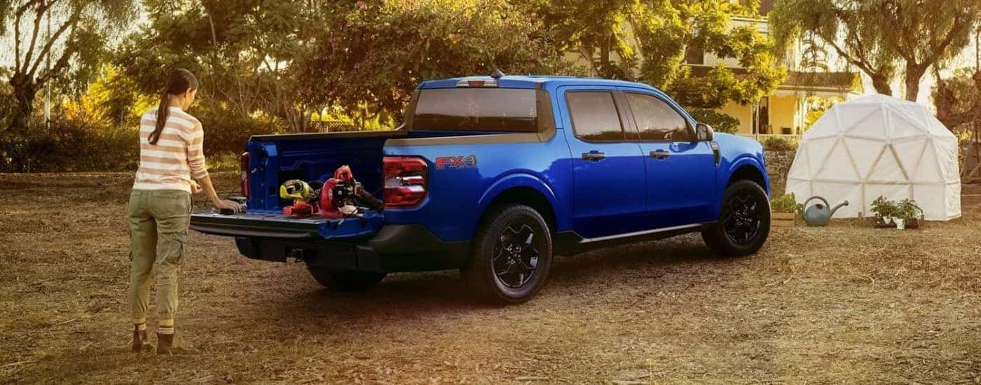 Person working out the tailgate of a blue 2024 Ford Maverick XLT.
