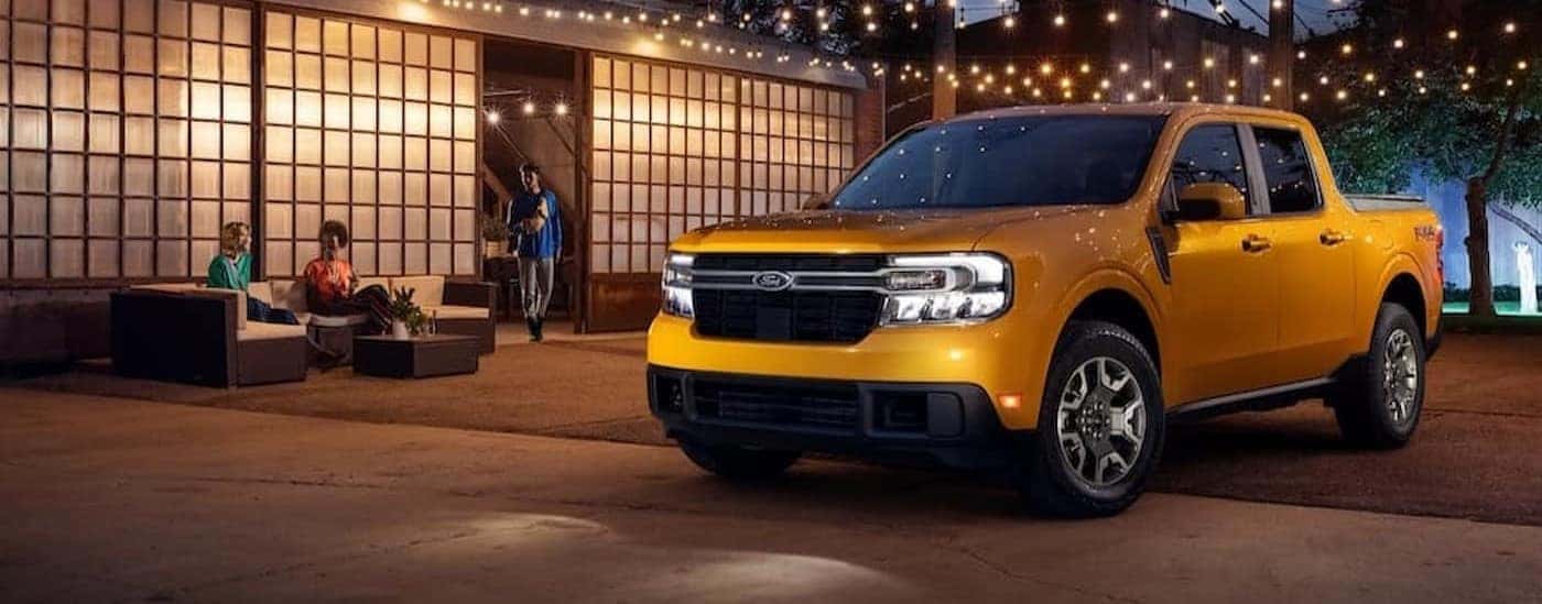 A yellow 2023 Ford Maverick parked near a gathering.