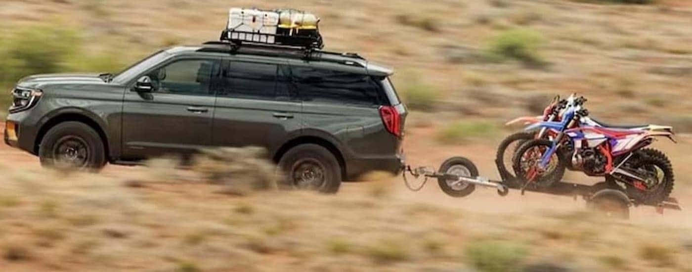 A green 2025 Ford Expedition towing a trailer off-road.