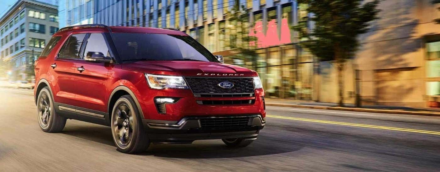 A red 2019 Ford Explorer driving on a city street.