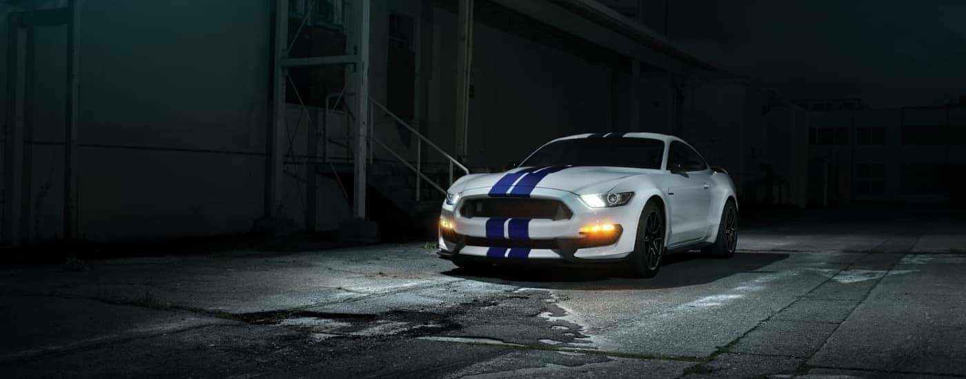 A white 2020 Ford Mustang GT350 is parked in an alleyway.