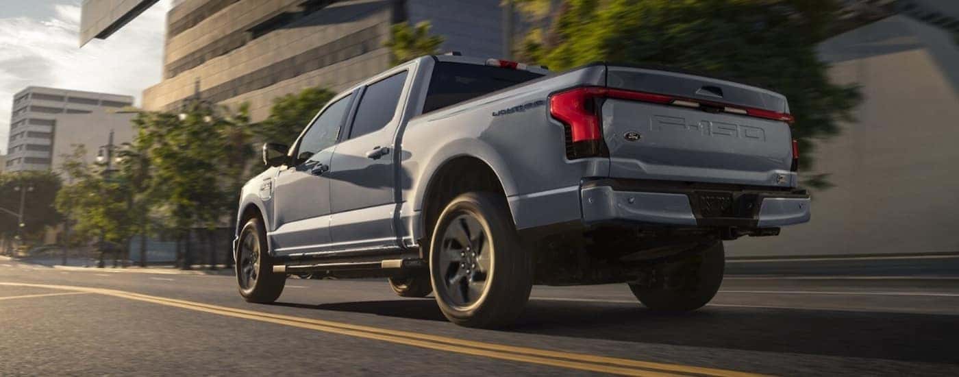 A grey 2022 Ford F-150 Lightning driving to look at a used Ford for sale near Travelers Rest.