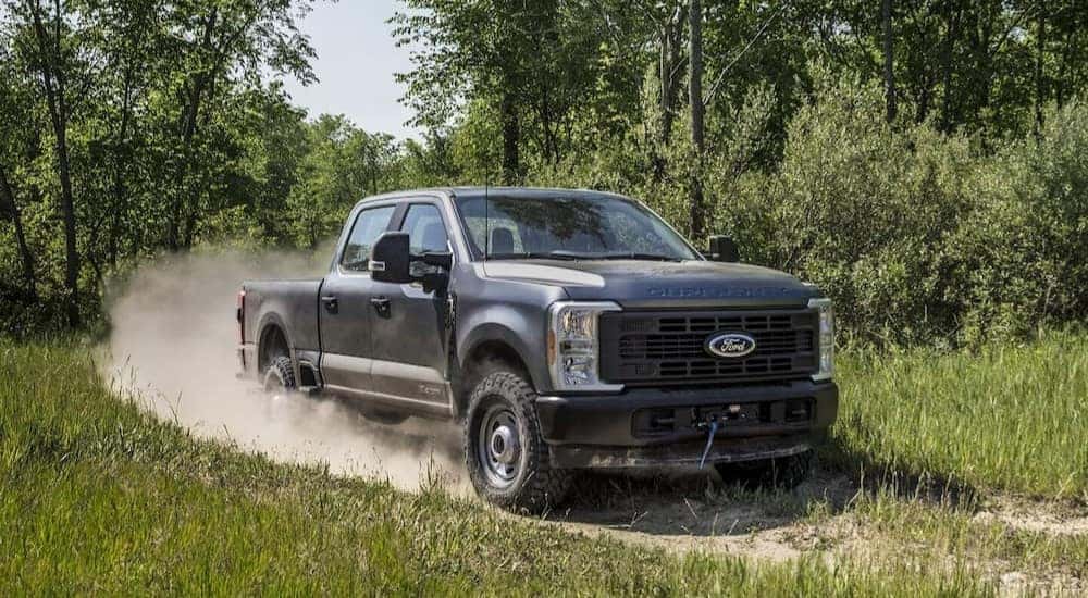 A gray 2025 Ford F-250 for sale driving on a dirt path.