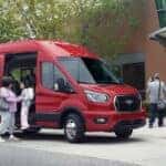A red 2025 Ford Transit Van parked outside of a school