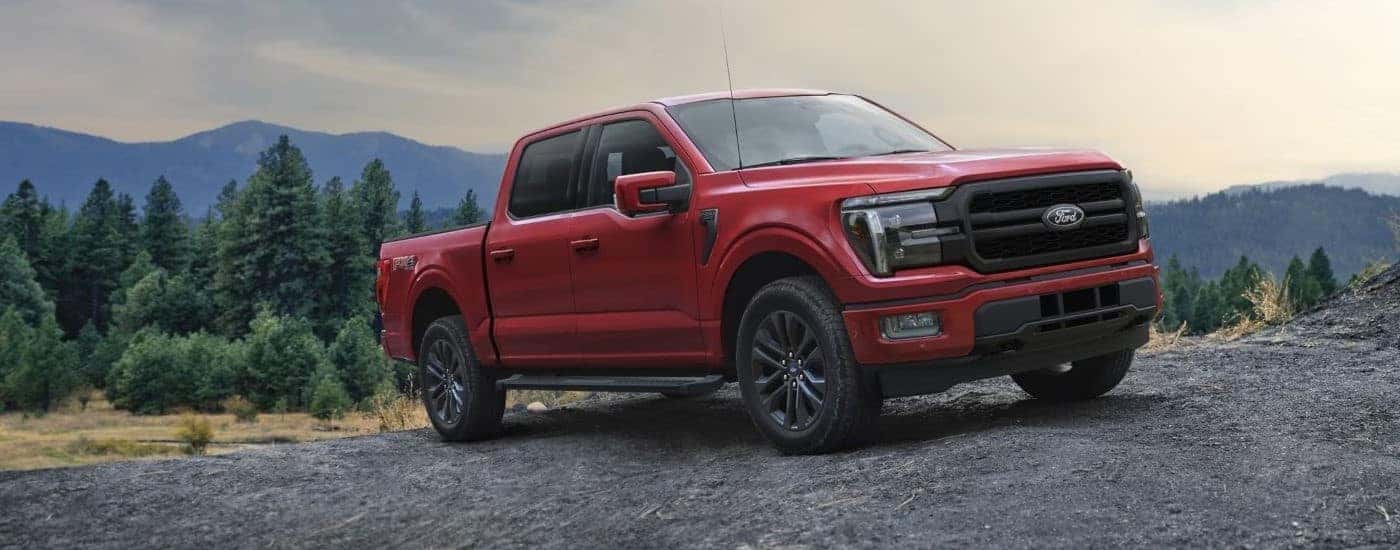 A red 2024 Ford F-150 parked off-road on gravel