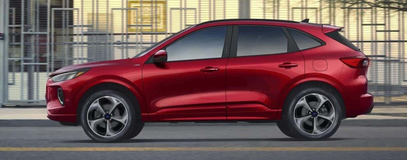 A red 2023 Ford Escape ST-Line driving in a city