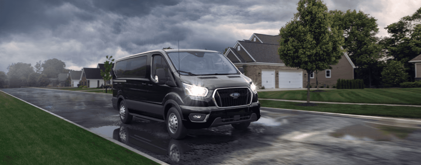 A black 2025 Ford Transit for sale in Hendersonville doing a test drive in the rain