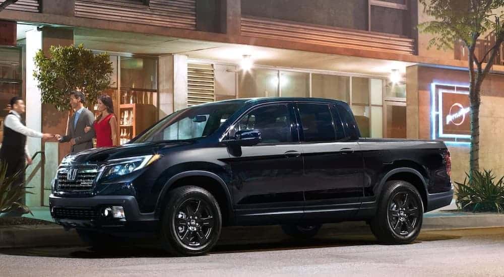 A black 2020 Honda Ridgeline parked near used trucks for sale.