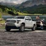 A white 2024 Toyota Tacoma towing a boat.
