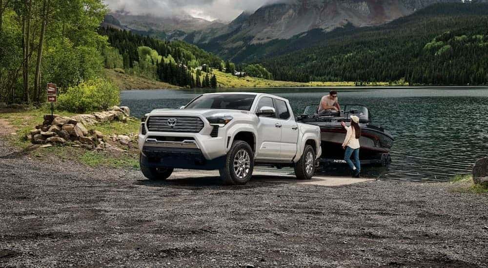 A white 2024 Toyota Tacoma towing a boat.