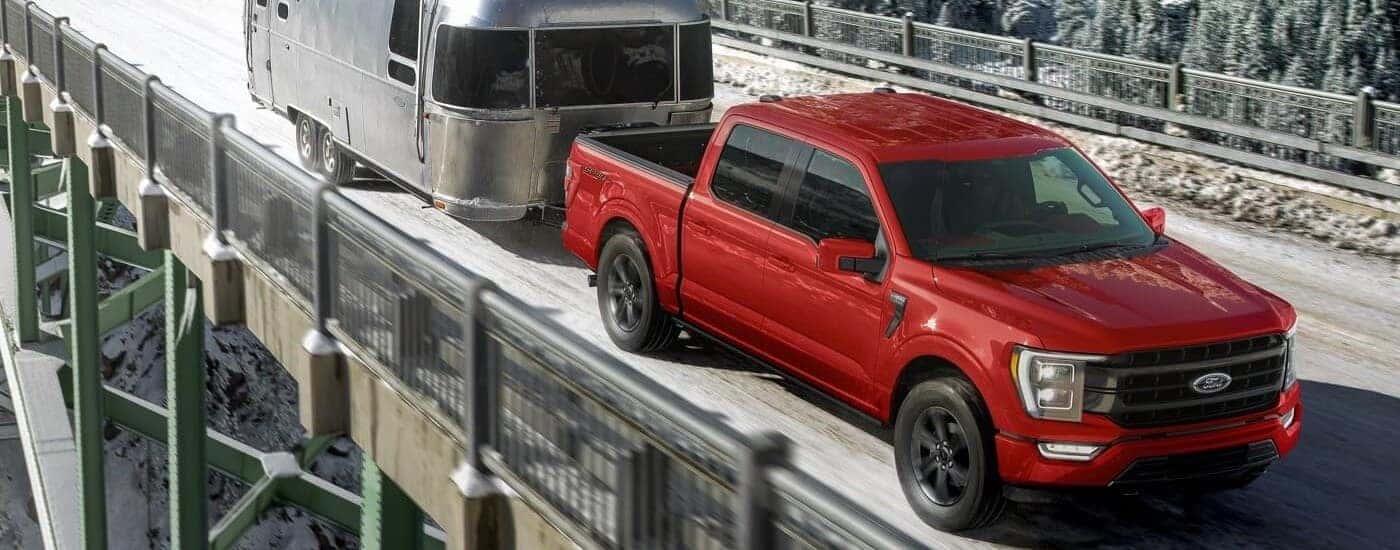 Red 2023 Ford F-150 Sport towing an airstream trailer.