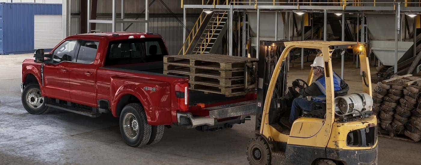 Rear of a red 2026 Ford F-350 hauling wooden pallets.