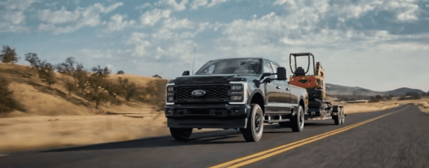 Grey 2026 Ford F-250 Super Duty towing a tractor