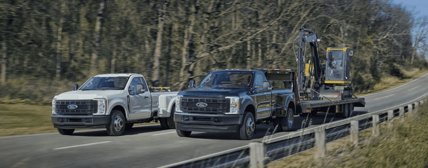 A white 2026 Ford F-350 Super Duty driving next to a blue 2026 Ford F-350 Super Duty