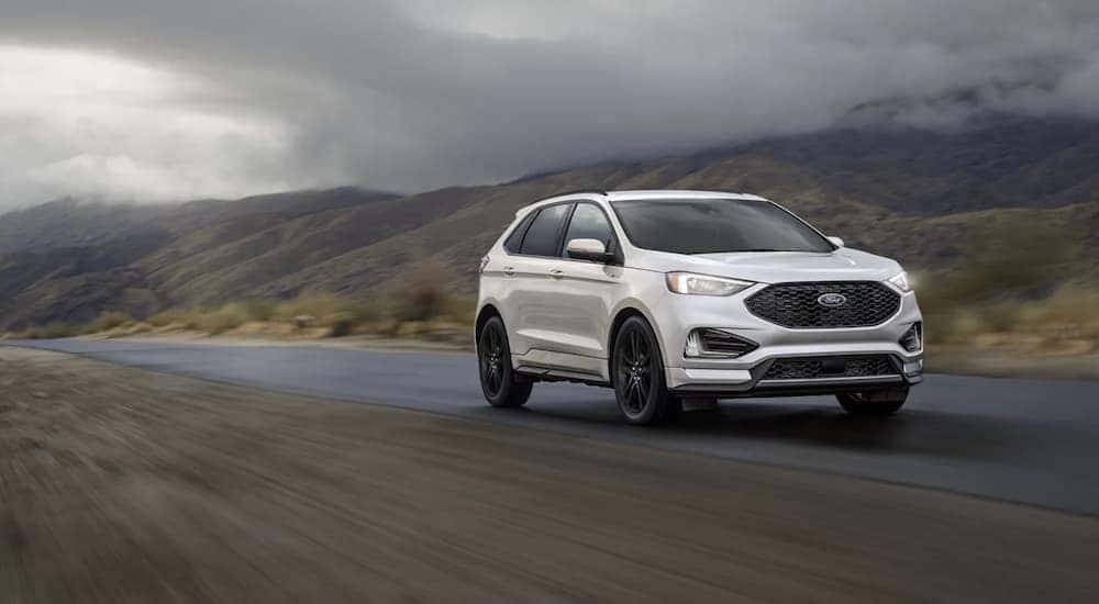 A white 2022 Ford Edge ST is driving on an open road.
