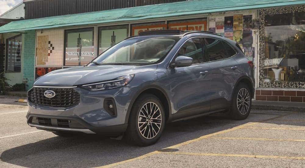 A grey 2023 Ford Escape is parked in front of a shop.